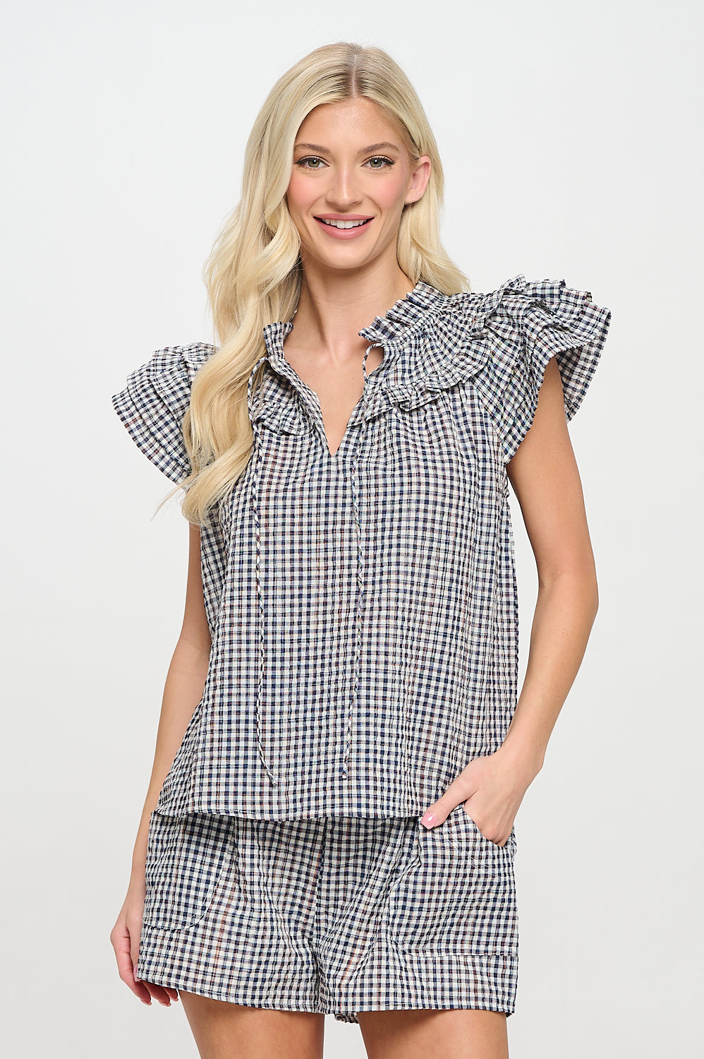 Model wearing a plaid ruffle-sleeve top with split neckline and flutter details.