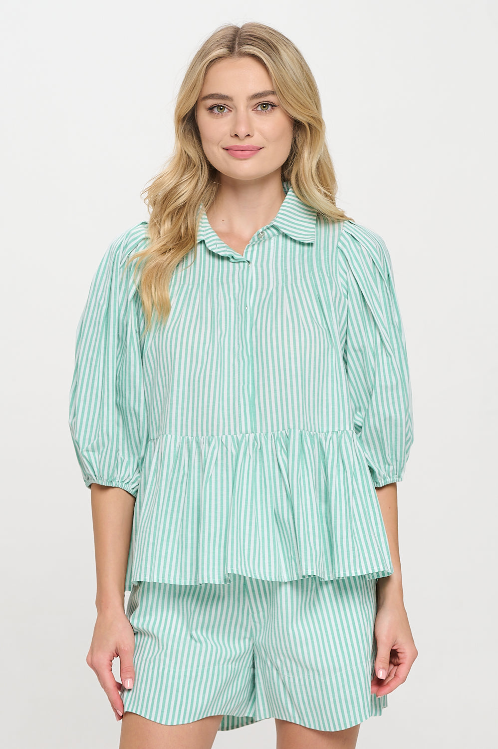 Model wearing a green and white striped peplum top with puff sleeves and a collared neckline.
