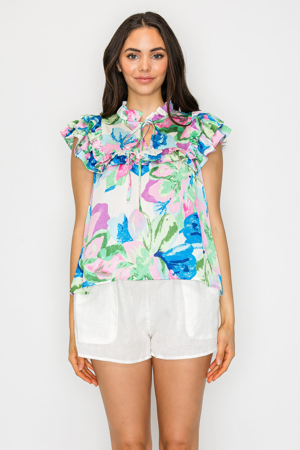 Woman wearing a floral ruffle blouse with flutter sleeves and a front tie keyhole neckline – breezy woven top for resort or summer outfits