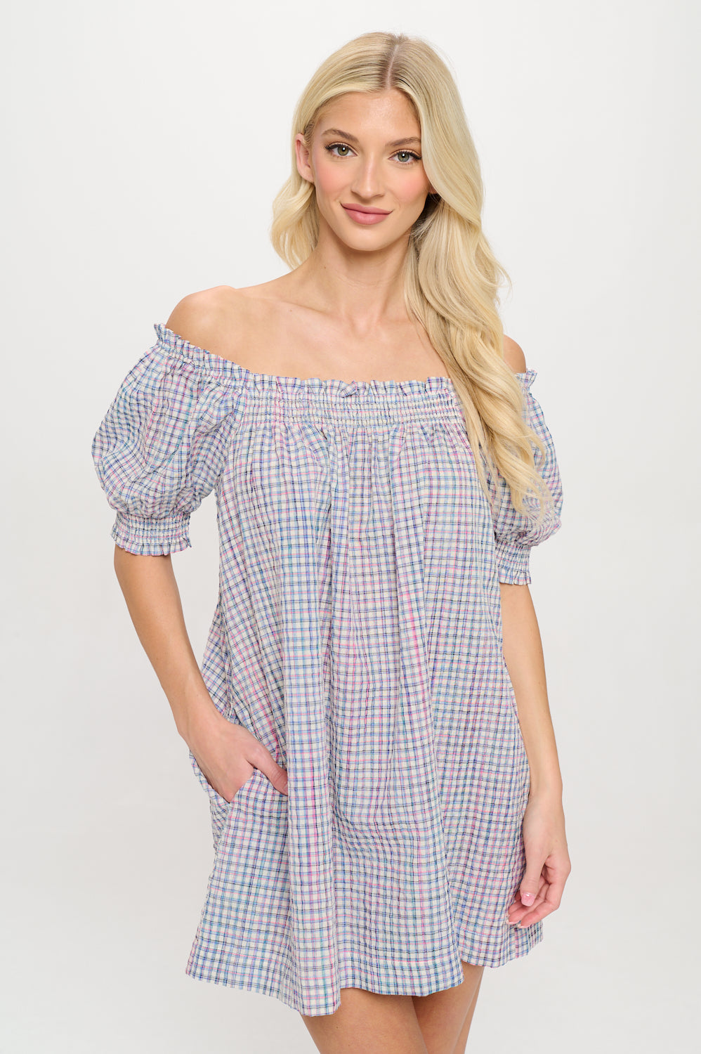 Model wearing an off-shoulder plaid mini dress with puff sleeves and relaxed fit, styled for vacation or summer resortwear.
