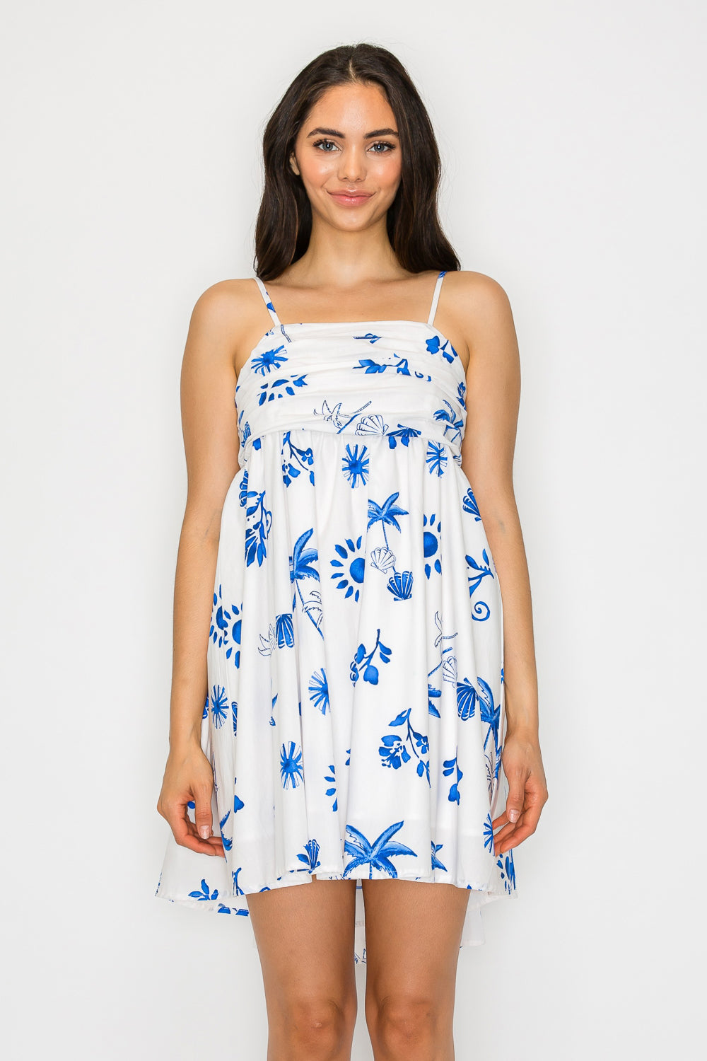 Woman wearing a white mini dress with blue island print and spaghetti straps – lightweight summer resortwear perfect for vacation styling