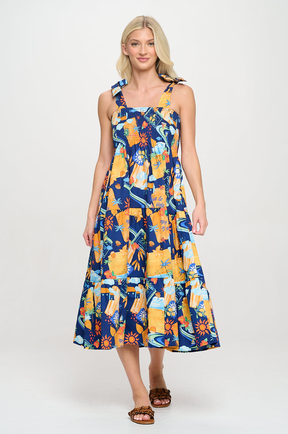 Model wearing a vibrant printed maxi dress with shoulder tie straps and smocked bodice, ideal for a resort or beach vacation.