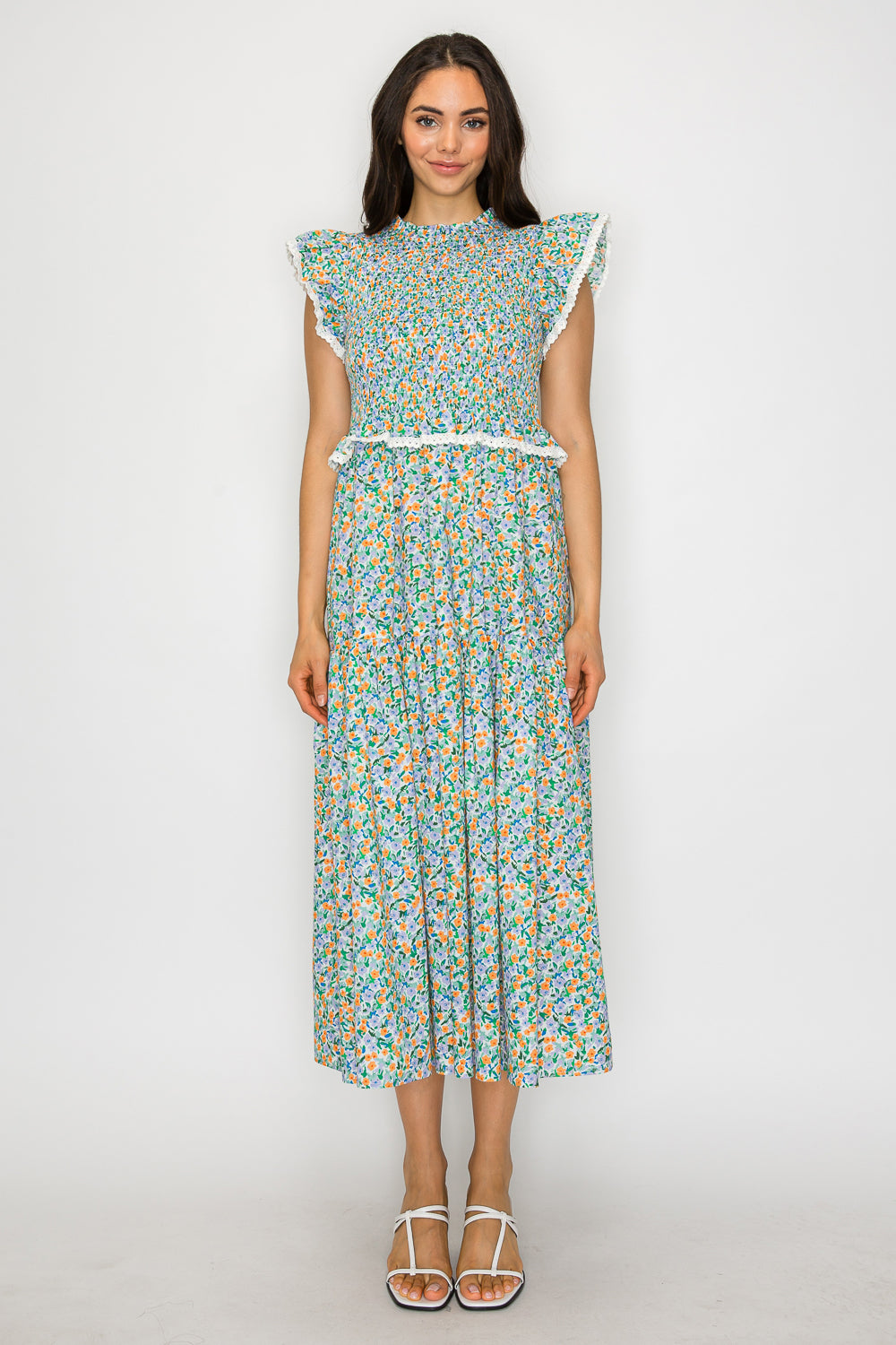 Woman wearing a smocked floral maxi dress with flutter sleeves and lace trim – romantic resortwear inspired by coastal gardens