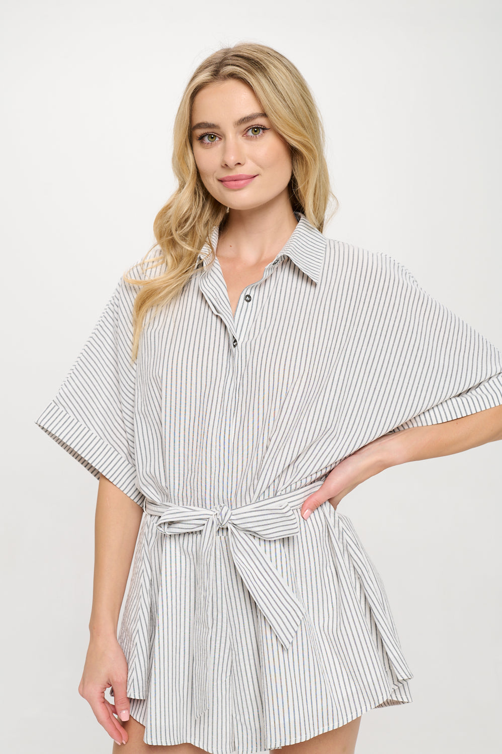 Model wearing a striped short-sleeve set with collared top, tie waist, and relaxed fit, styled for coastal summer resortwear.