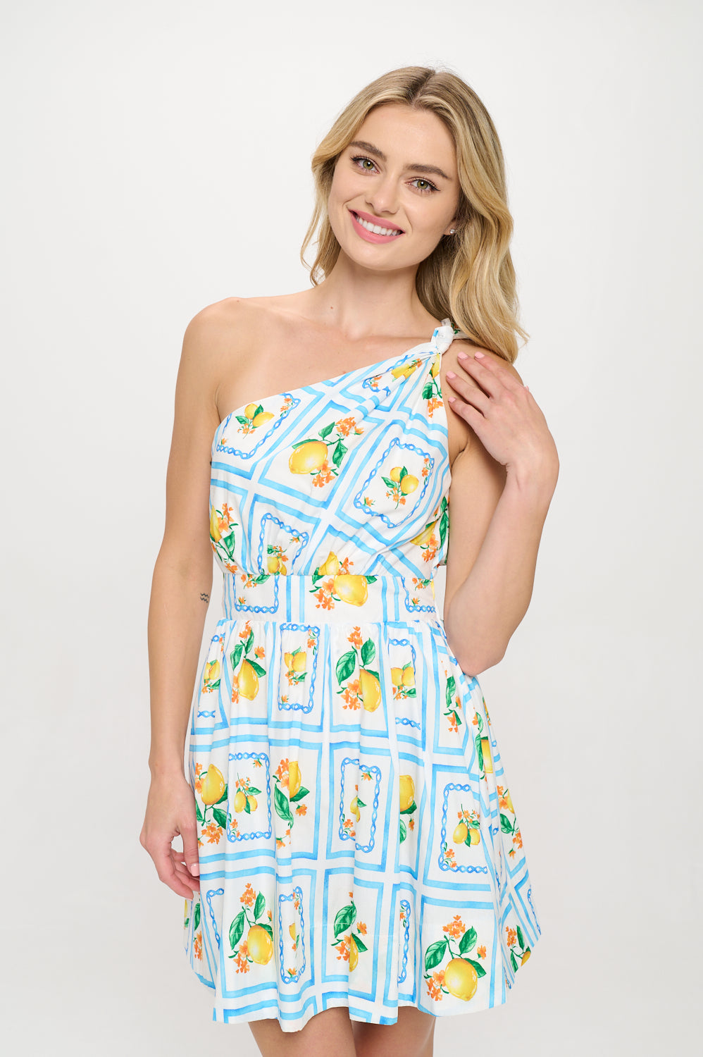 Model wearing a one-shoulder lemon-print mini dress with elastic waist and flared skirt—styled for summer vacation or resortwear.