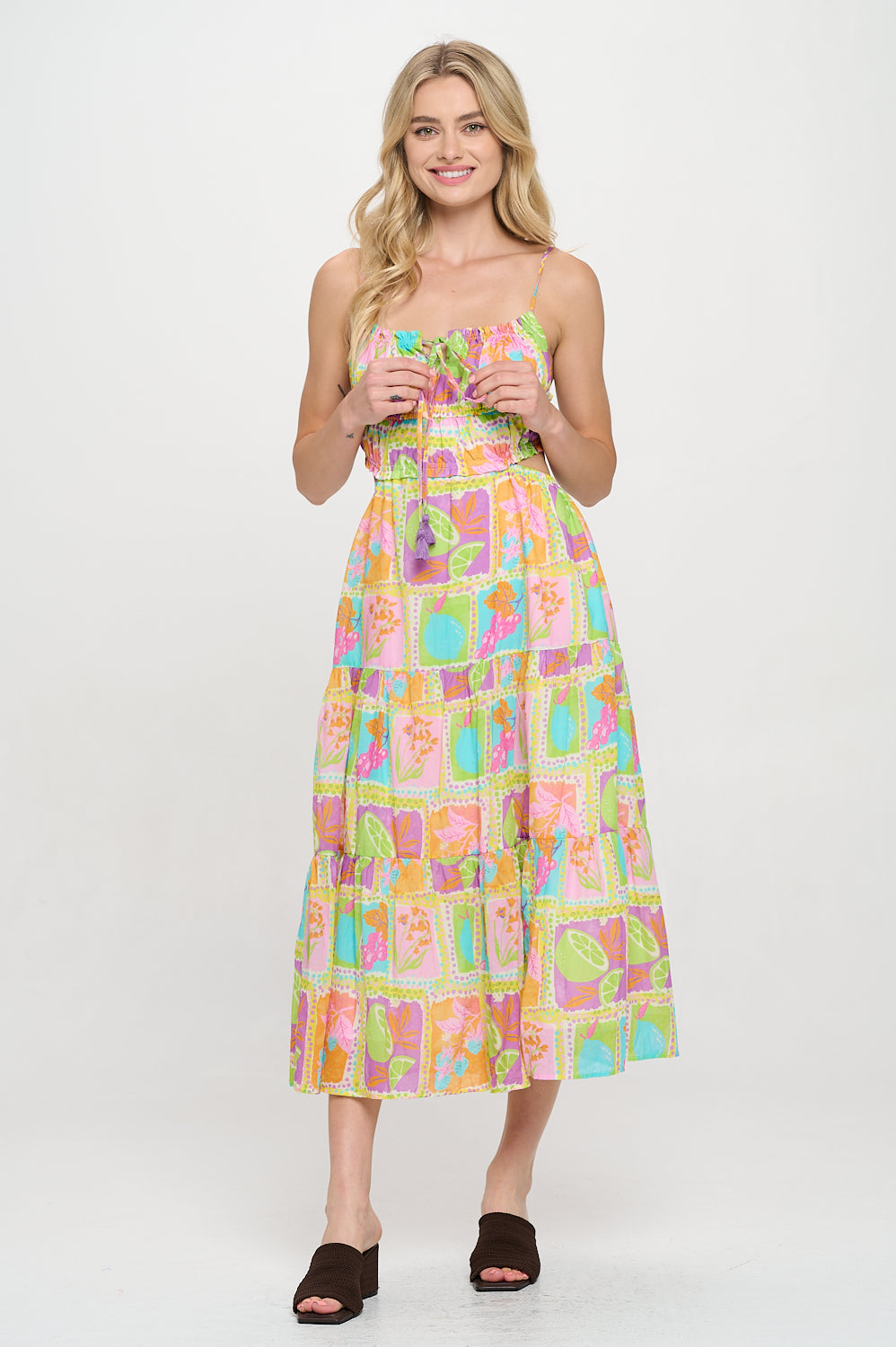 Model wearing a vibrant tropical tile-print maxi dress with spaghetti straps and a ruched bodice. Ideal for warm-weather getaways and resort styling.