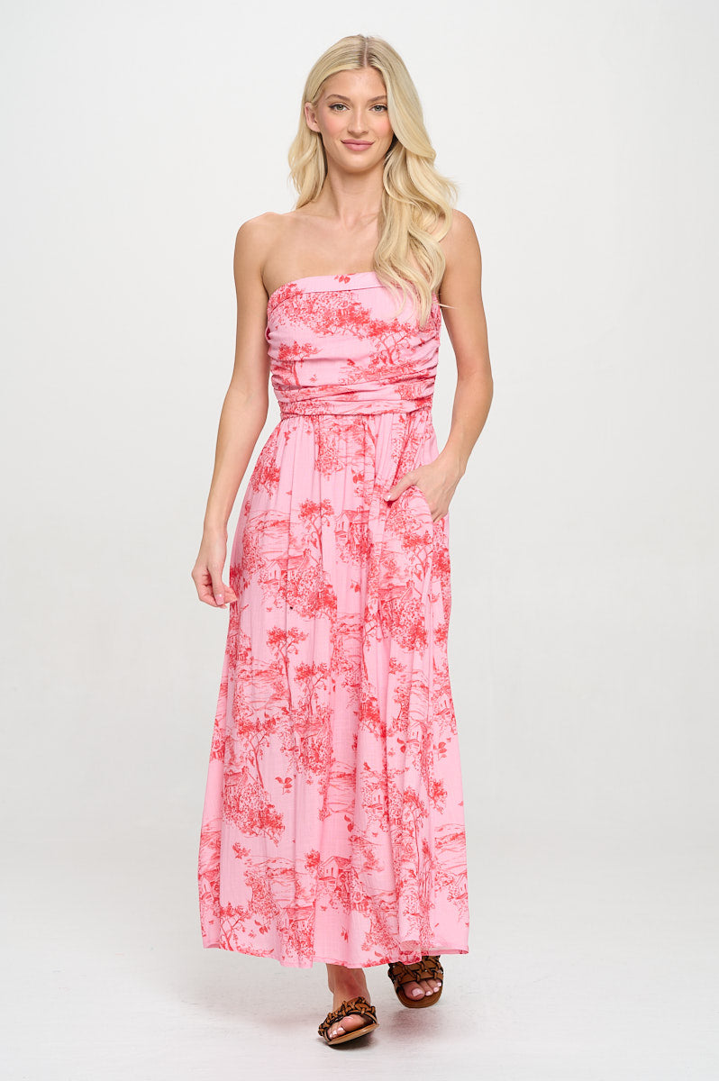 Woman wearing strapless pink toile maxi dress with empire waist and side pockets
