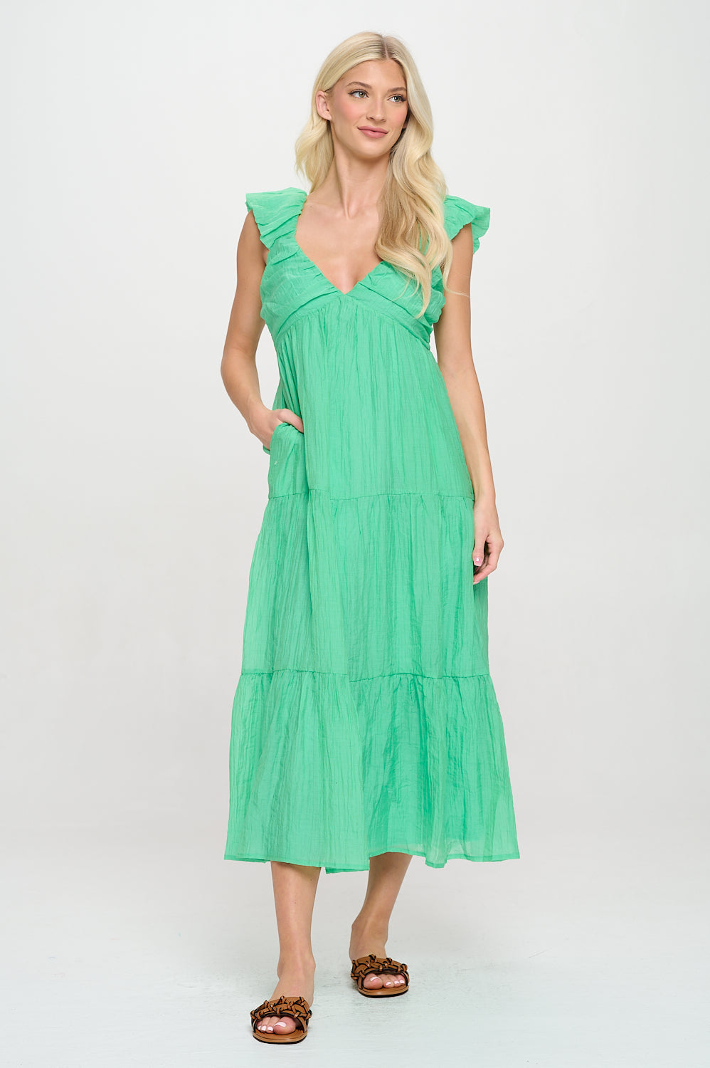 Model wearing a green tiered maxi dress with ruffle sleeves, V-neckline, and pockets—styled for coastal vacations or summer resortwear.