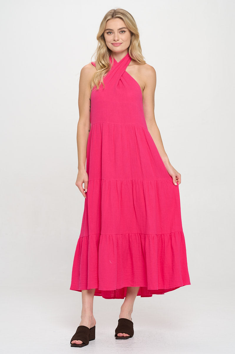 Model wearing a fuchsia halter maxi dress with a tiered skirt and twisted neckline.