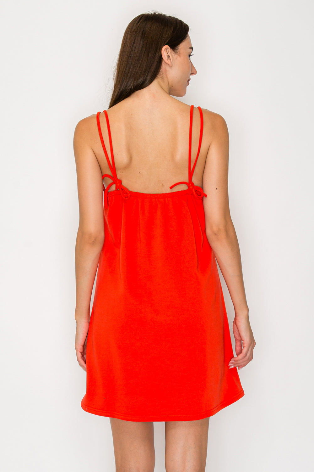 Woman wearing a bright red slip dress against a white background