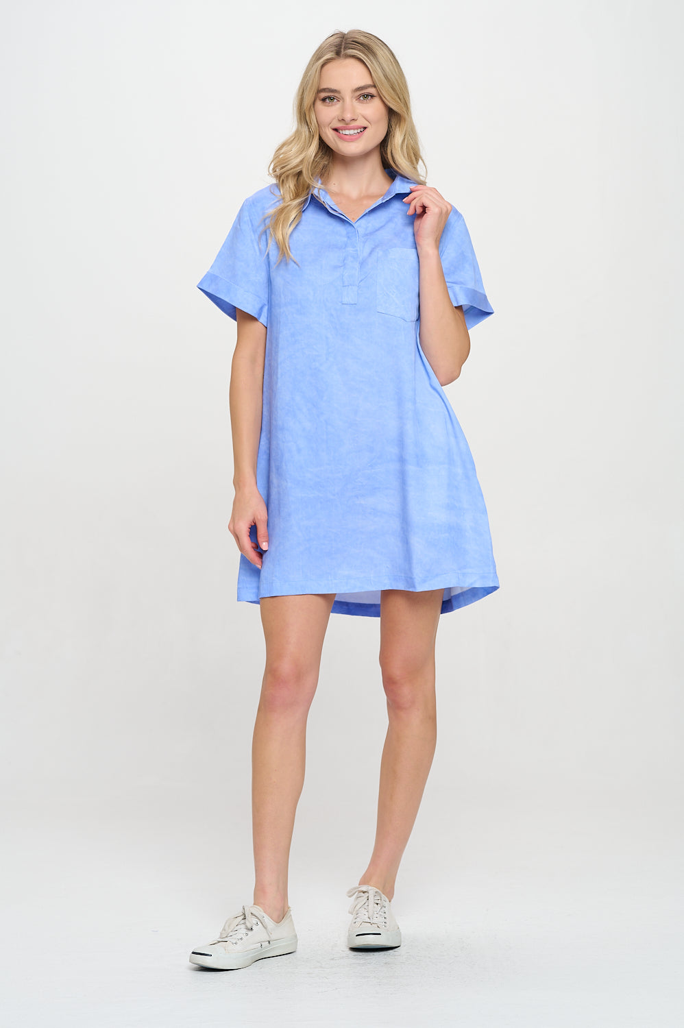 Model wearing a relaxed shirt dress with short sleeves and front pocket in soft suede-like fabric.