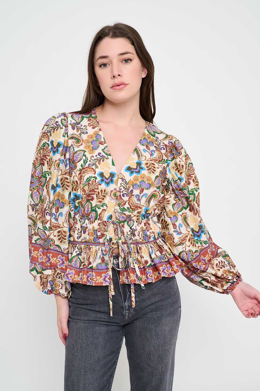Model wearing printed peplum blouse with long sleeves and V-neckline