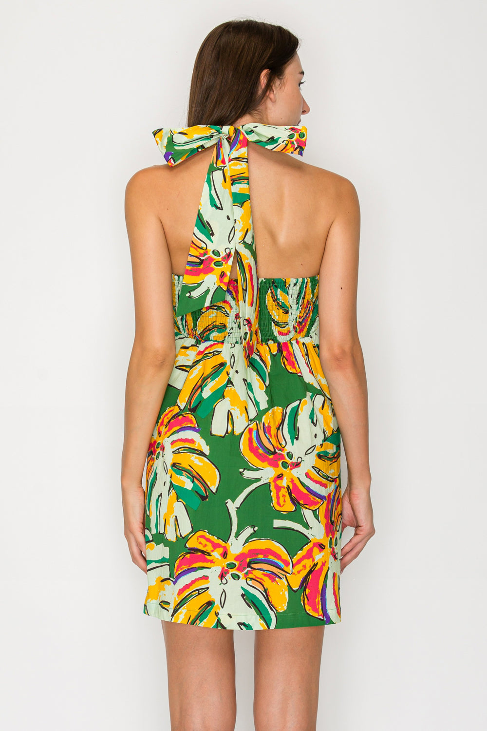 Woman wearing a colorful halter neck dress with a banana leaf pattern on a white background