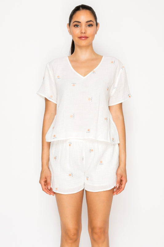 Model wearing the Dreams of Flora Set, a white double gauze two-piece set with delicate floral embroidery.