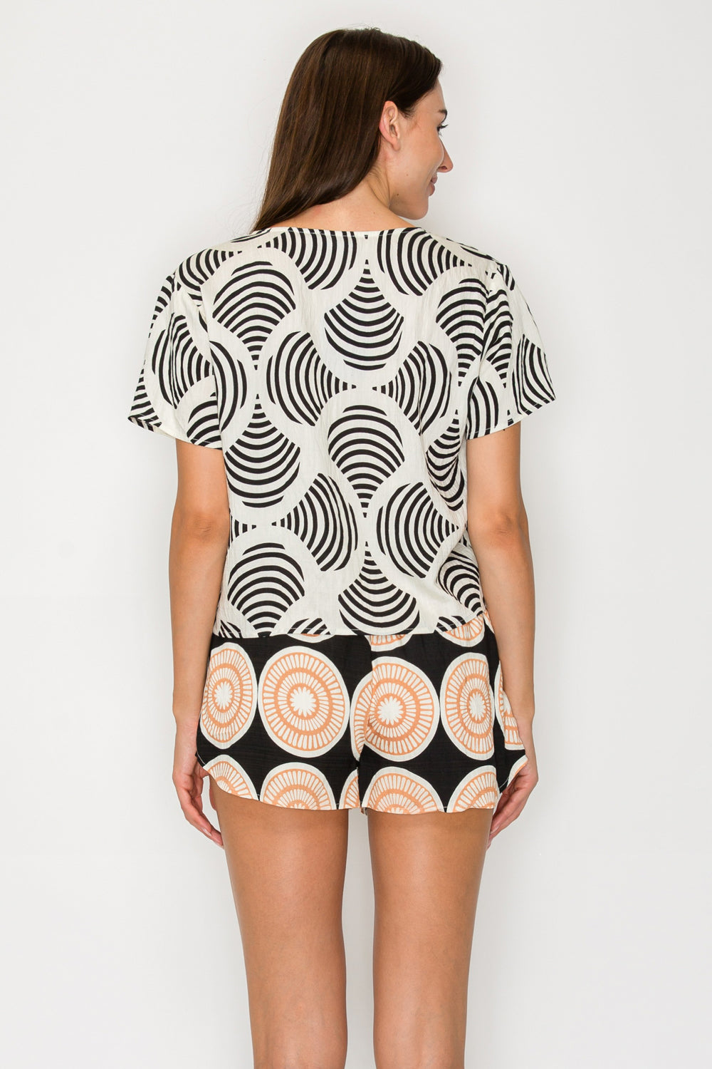Woman wearing a black and white patterned outfit on a plain background