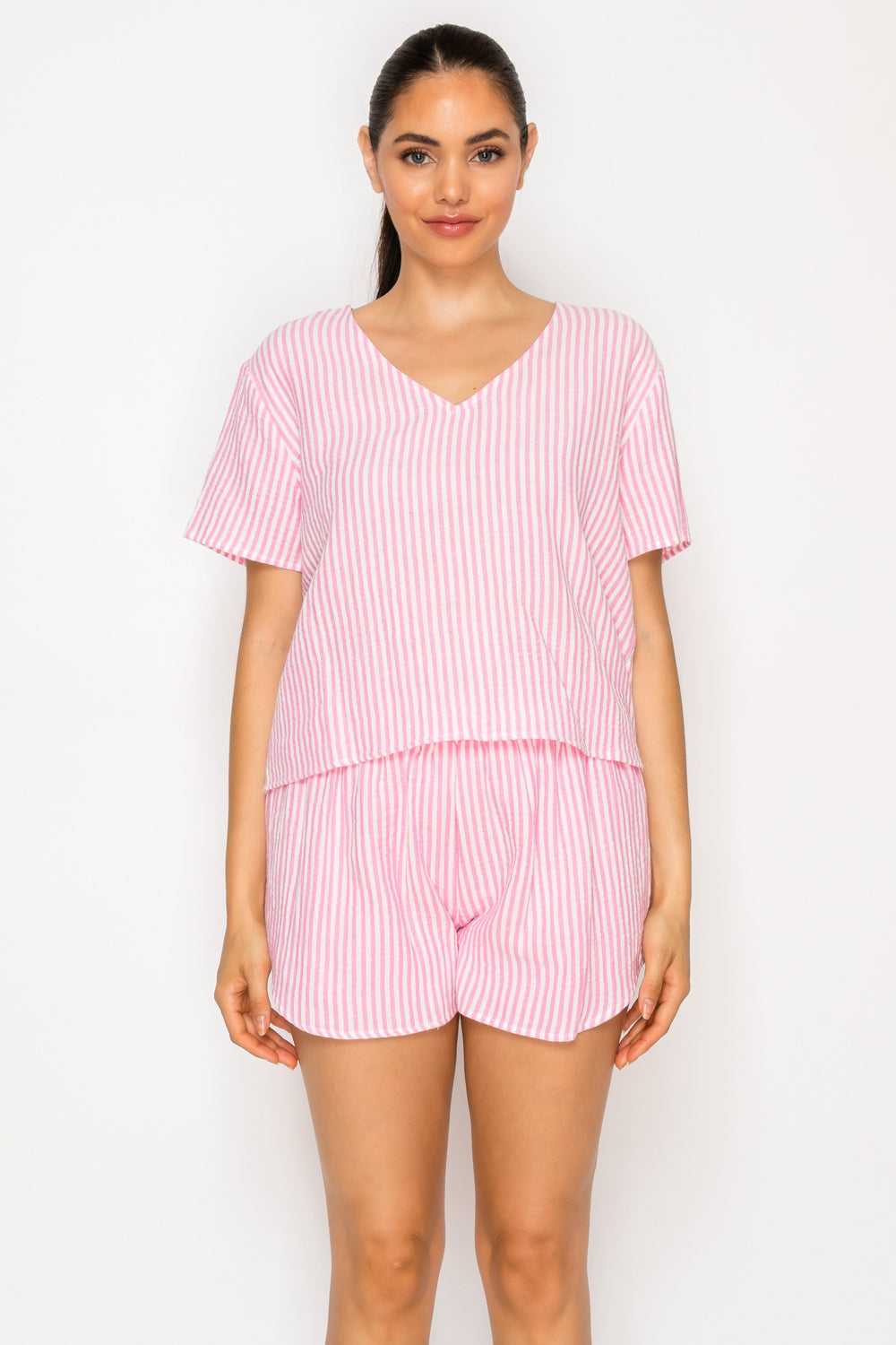 Model wearing the Pink Gauze Stripe Set, a two-piece coordinated lounge set featuring a pink and white striped V-neck short-sleeve top and matching shorts.