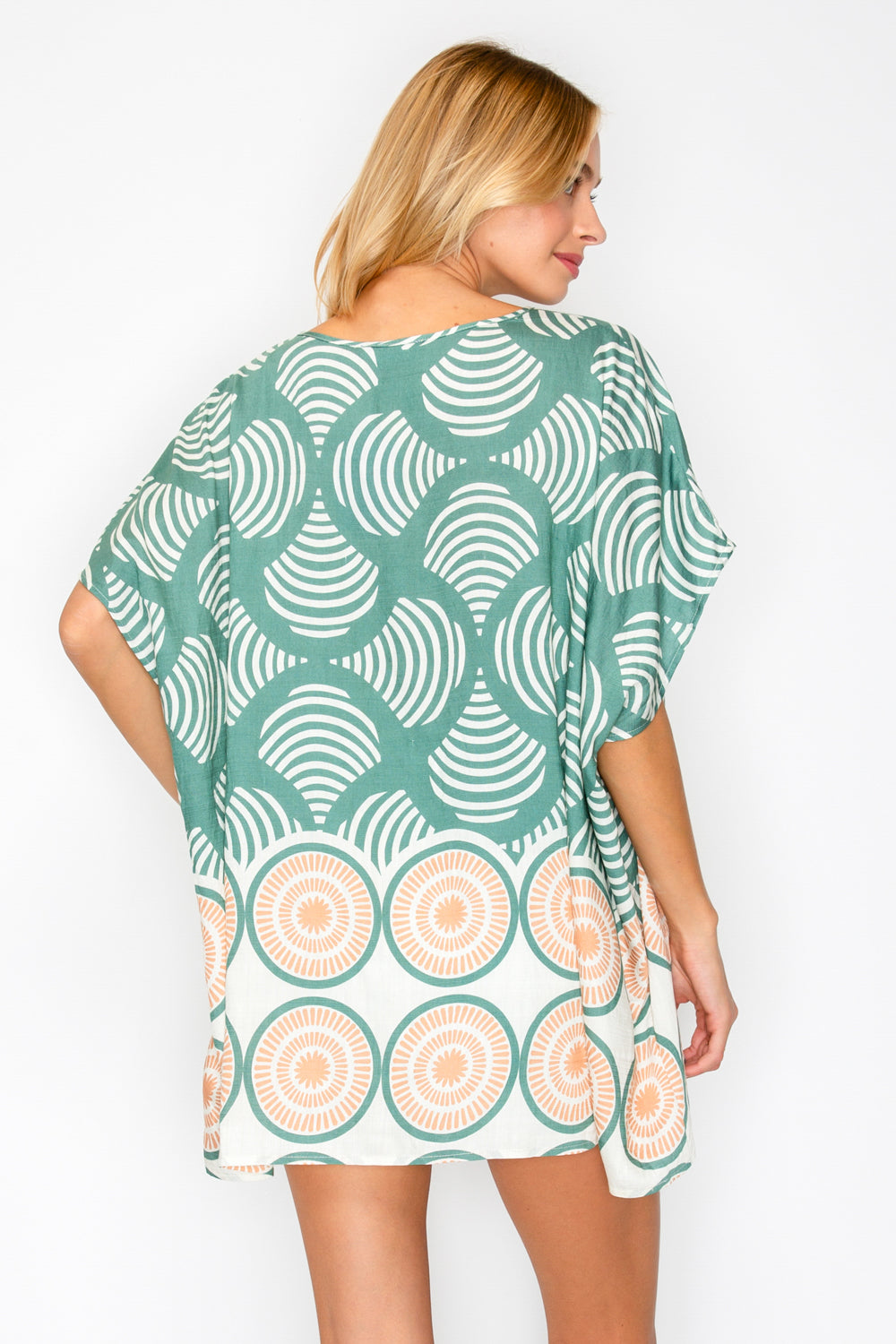 Woman wearing a green and white patterned dress on a plain background