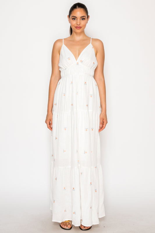 Model wearing the Dreams of Floral Maxi Dress, a white double gauze dress with delicate floral embroidery, a V-neck, and a tiered skirt.