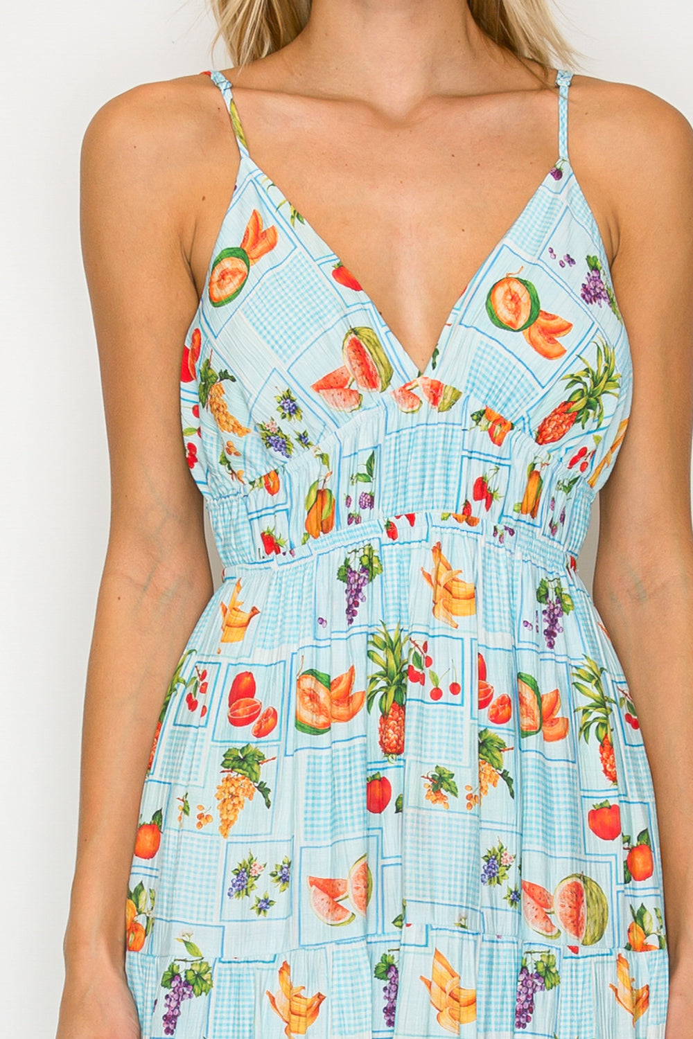 Woman wearing a dress with a fruit pattern on a plain background