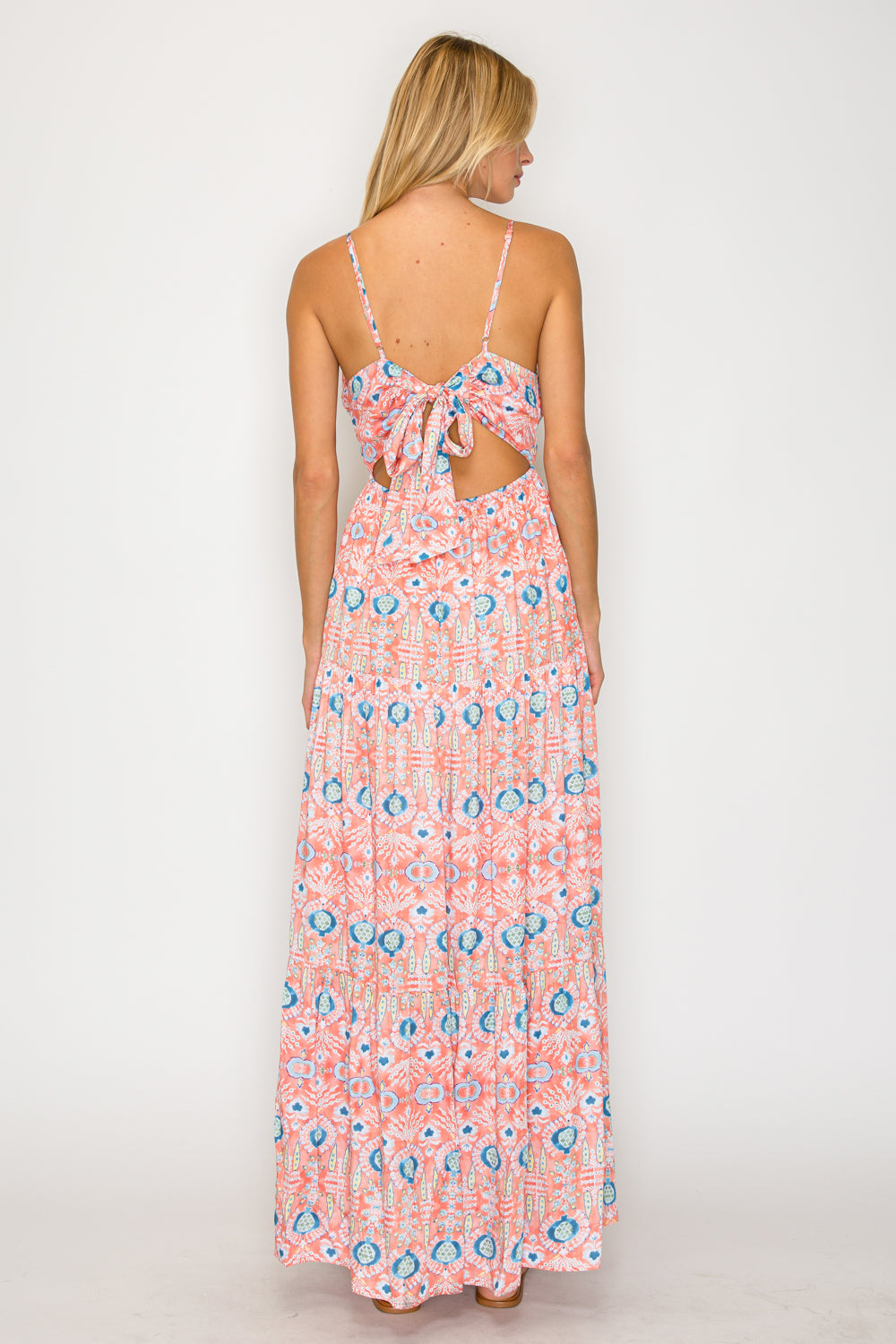 Woman wearing a pink floral dress with cut-out back on a white background