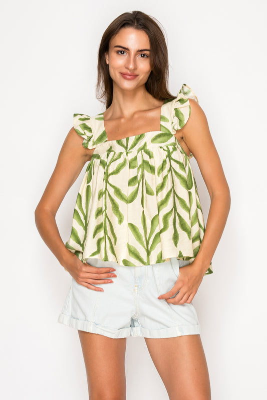 Model wearing the Olive Fern Top, a cream and green leaf print babydoll top with a square neck and ruffle sleeves.