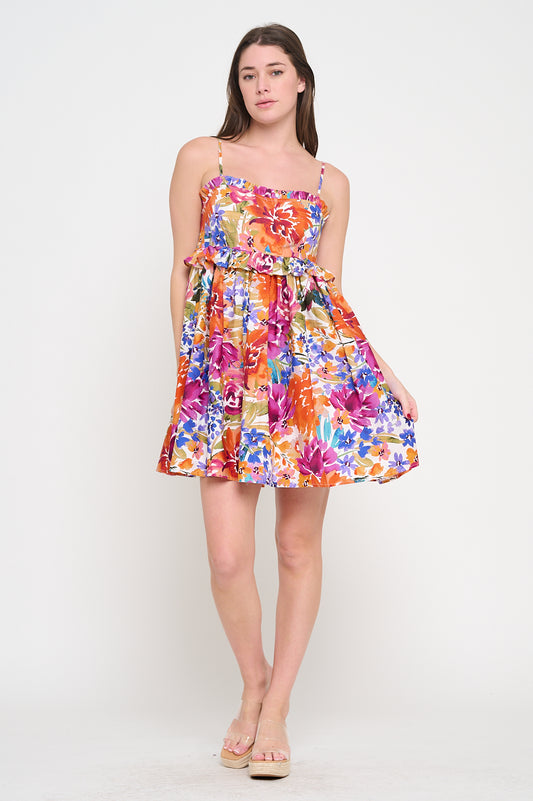 Front view of a model wearing a colorful floral tube dress with thin straps and a ruffle detail across the bodice.