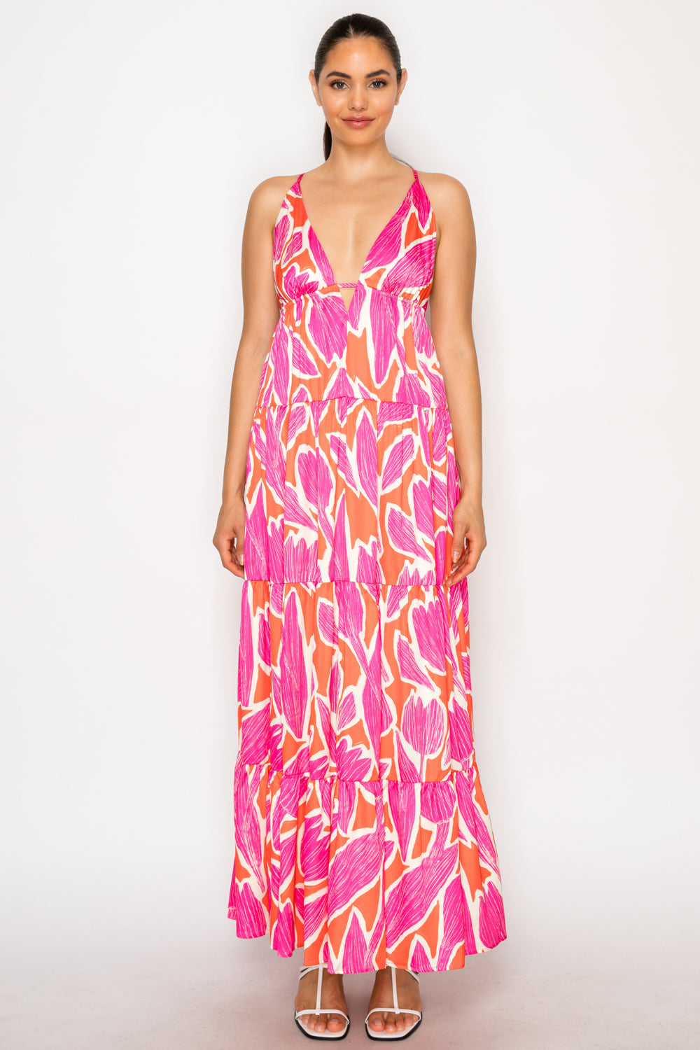 Model wearing Thalia's Tulip Maxi Dress, a white floor-length tiered dress with a vibrant magenta and orange abstract floral print and a deep V-neckline.