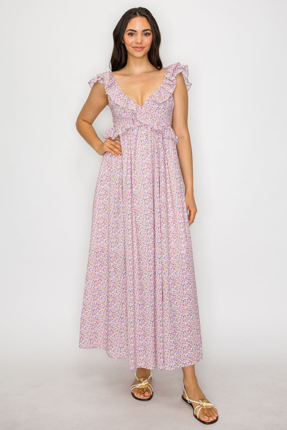 Model wearing a floral maxi dress with ruffle straps, deep V neckline, and bow-tied open back detail.