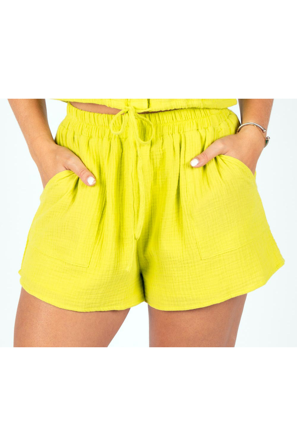 Close-up of high-rise yellow gauze shorts with drawstring waist and front patch pockets.