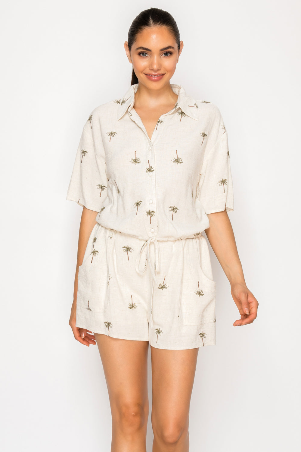 Model wearing the Drifting Palms Shirt, a cream-colored button-front top with a palm tree print.