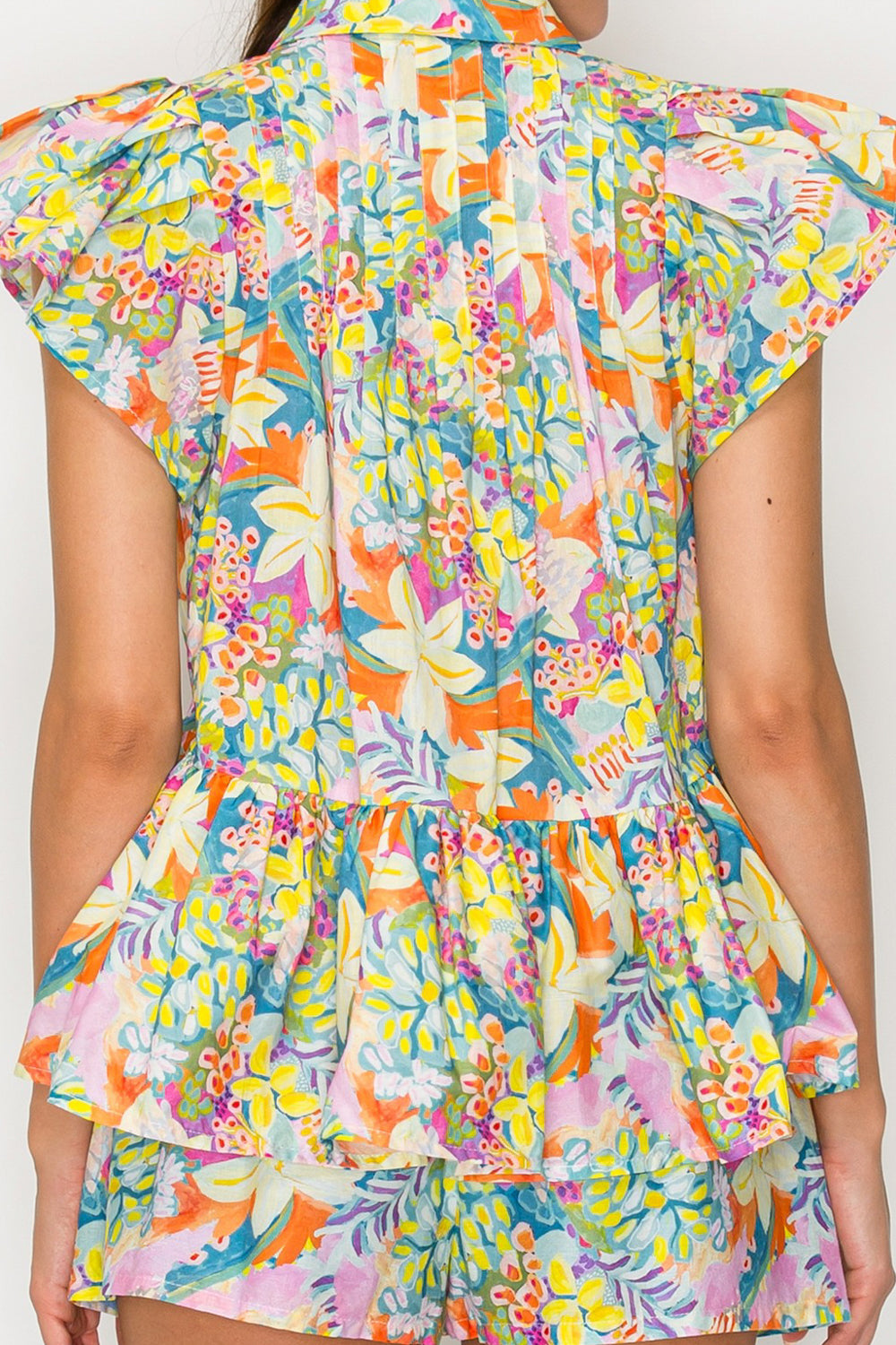 Colorful floral dress with ruffled layers on a plain background