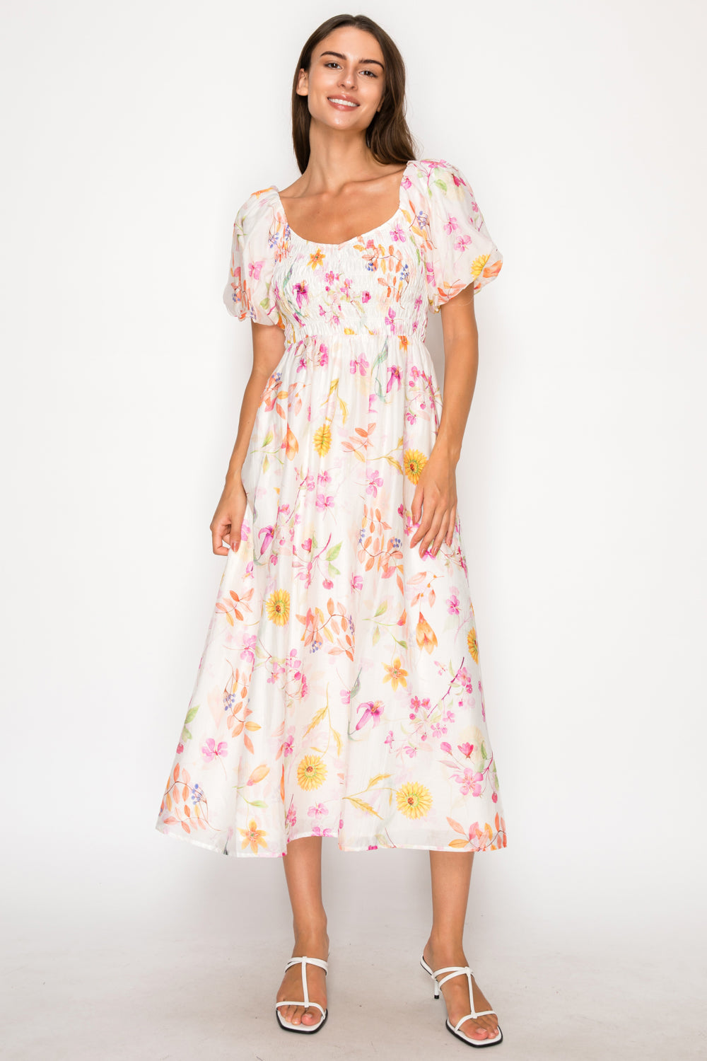 Model wearing the Sirena Garden Mini Dress, a white baby-doll style mini dress with a colorful dainty floral print and thin adjustable straps.