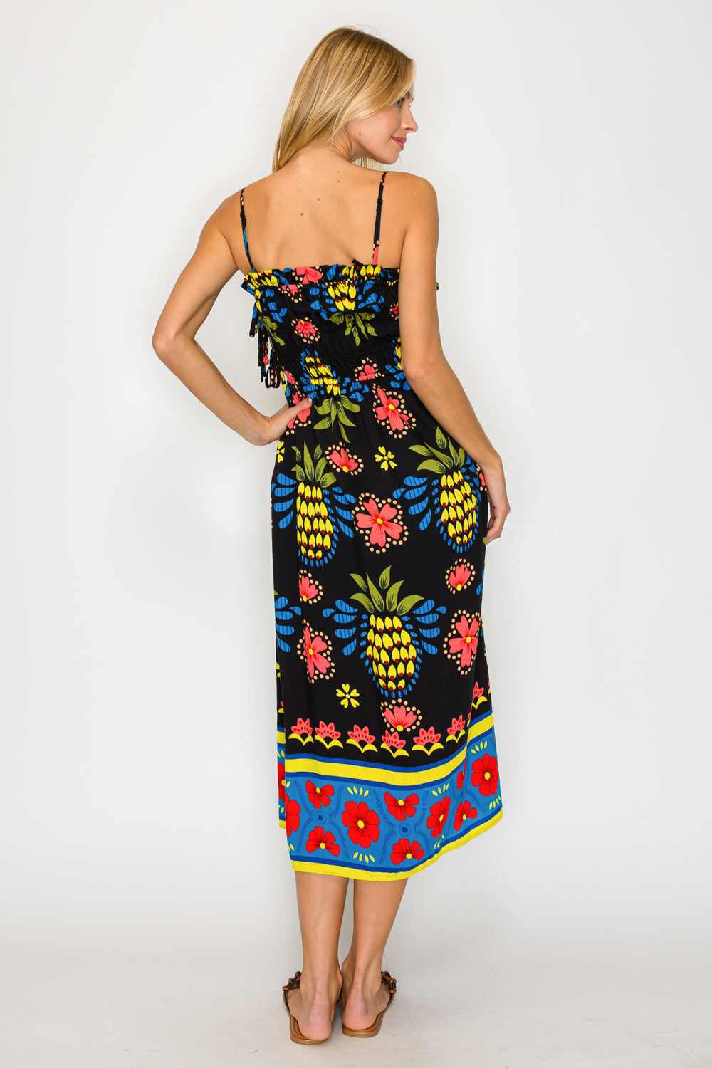 Woman wearing a colorful dress with pineapple and floral pattern on a white background