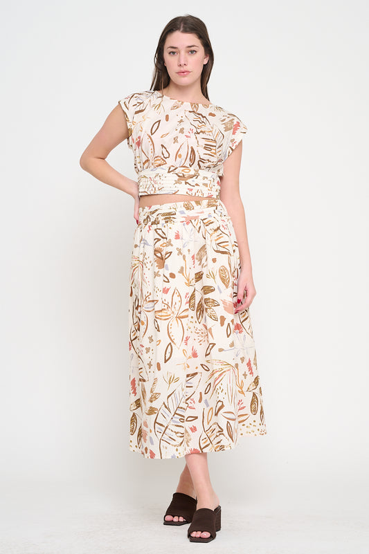 Woman wearing a matching set with a cropped cap sleeve top and high-waisted midi skirt, featuring an abstract botanical print in earthy tones.