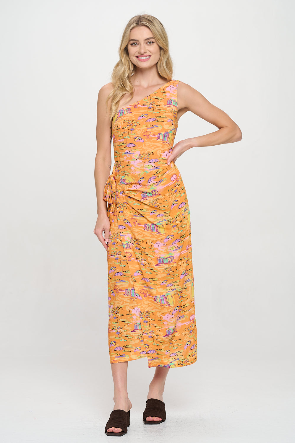 Model wearing a printed one-shoulder midi dress with side tie and wrap silhouette. Styled for resort vacations or coastal evenings.
