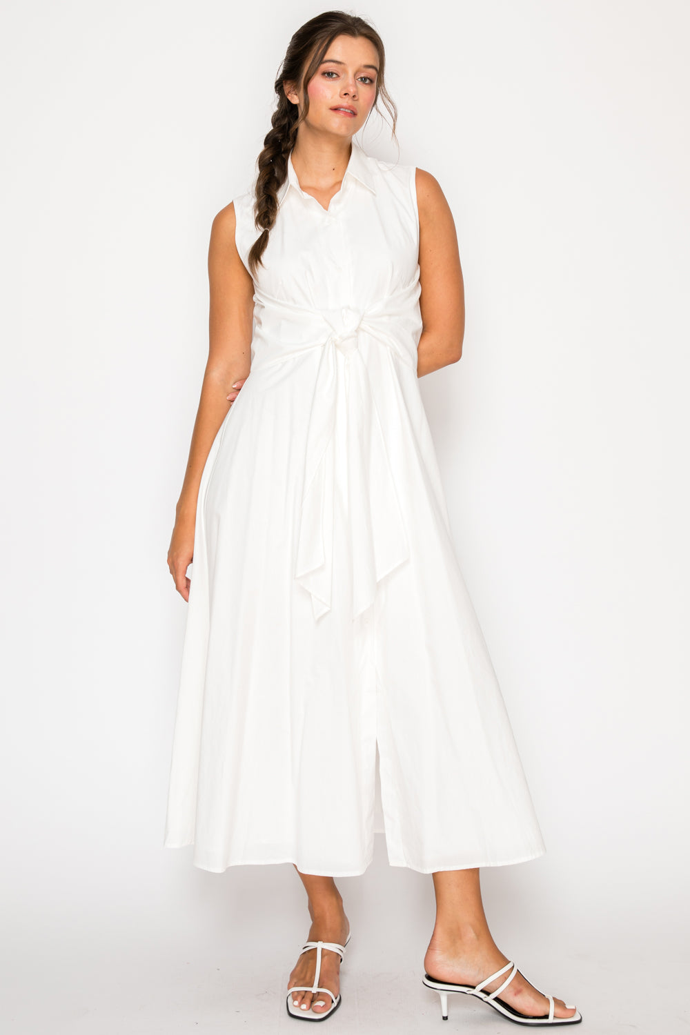 Model wearing the White Poplin Shirt Dress, a sleeveless white midi dress with a collar and a tie-waist detail.