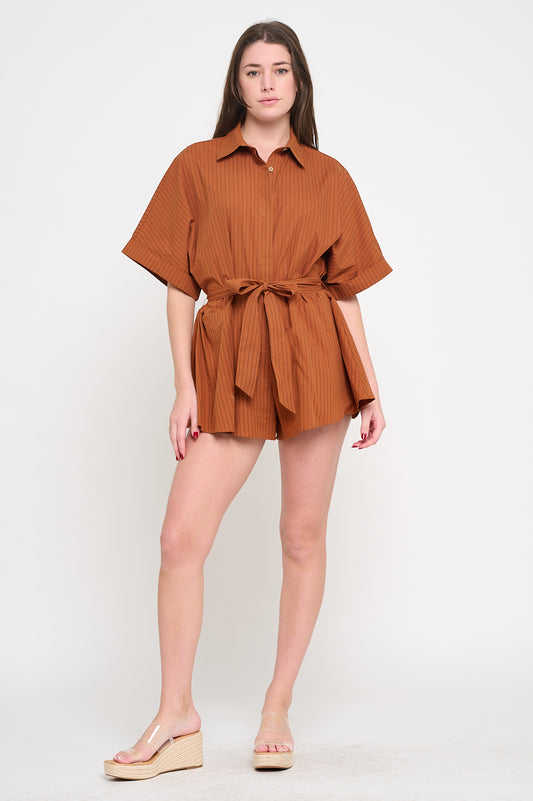 Woman wearing a terracotta short-sleeve romper with tonal stripes, collared neckline, tie waist, and relaxed fit shorts.