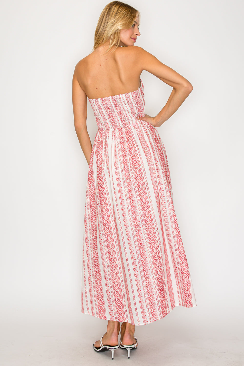 Woman wearing a strapless red and white patterned dress on a plain background
