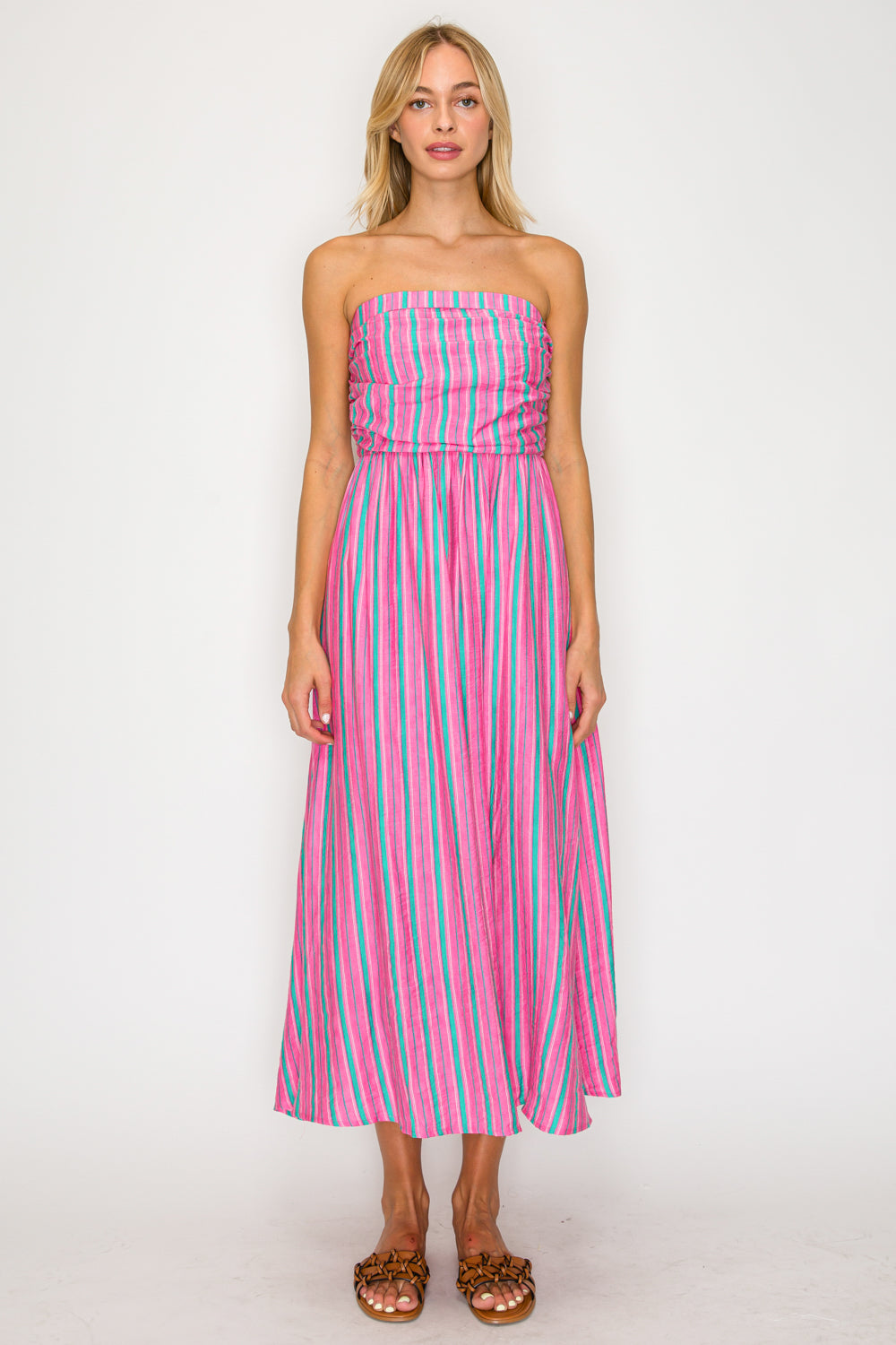 Woman wearing a strapless pink and blue striped dress on a white background