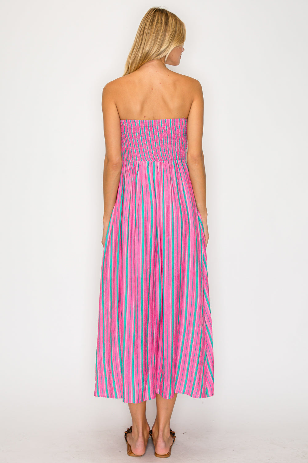 Woman wearing a pink and green striped strapless dress on a white background
