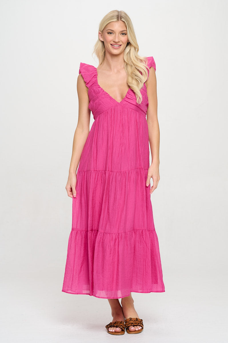 Model wearing a fuchsia ruched maxi dress with flutter sleeves and tiered skirt.