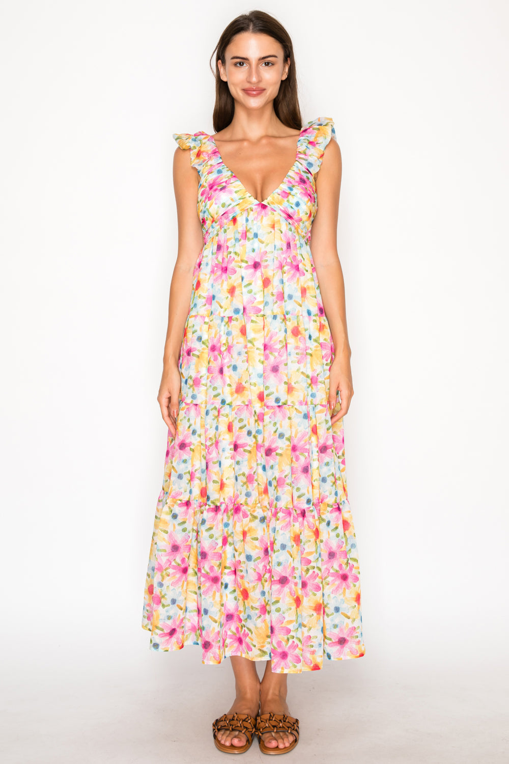 Model wearing the Thalia's Meadow Maxi Dress, a white floor-length dress with a vibrant pink and yellow floral print, featuring ruffled sleeves and a tiered skirt.