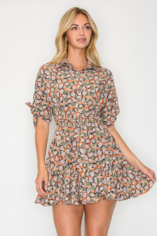 Model wearing the Autumn Pebble Shirt Dress, a printed mini dress with a collar, smocked waist, and tie-details on the sleeves.