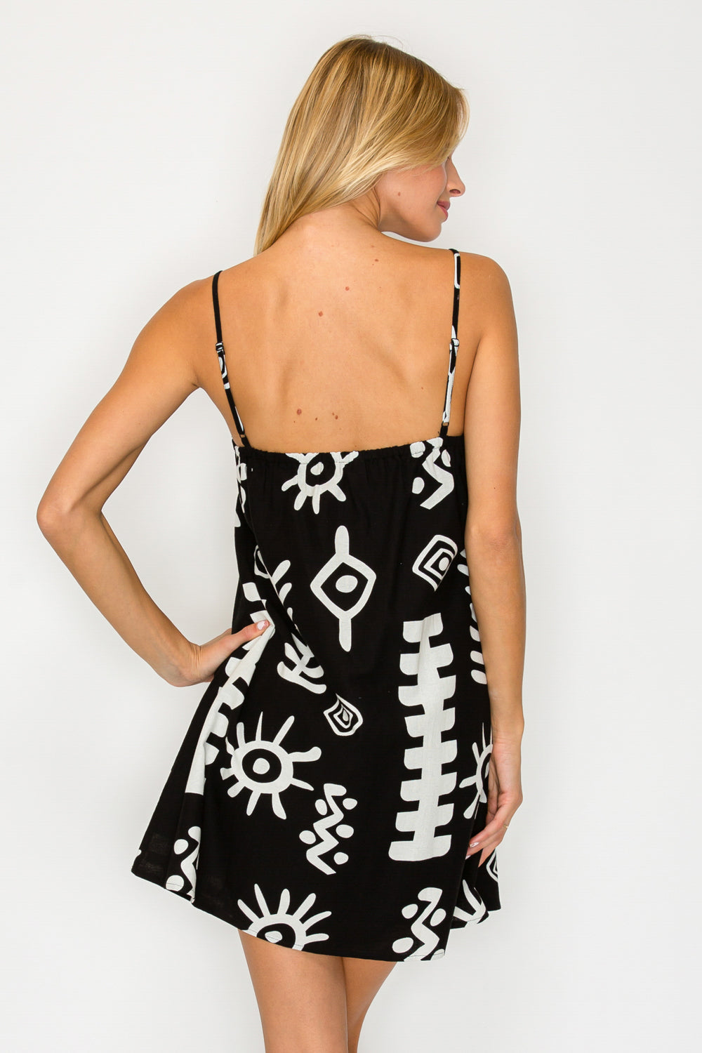 Woman wearing a black dress with white patterns on a plain background