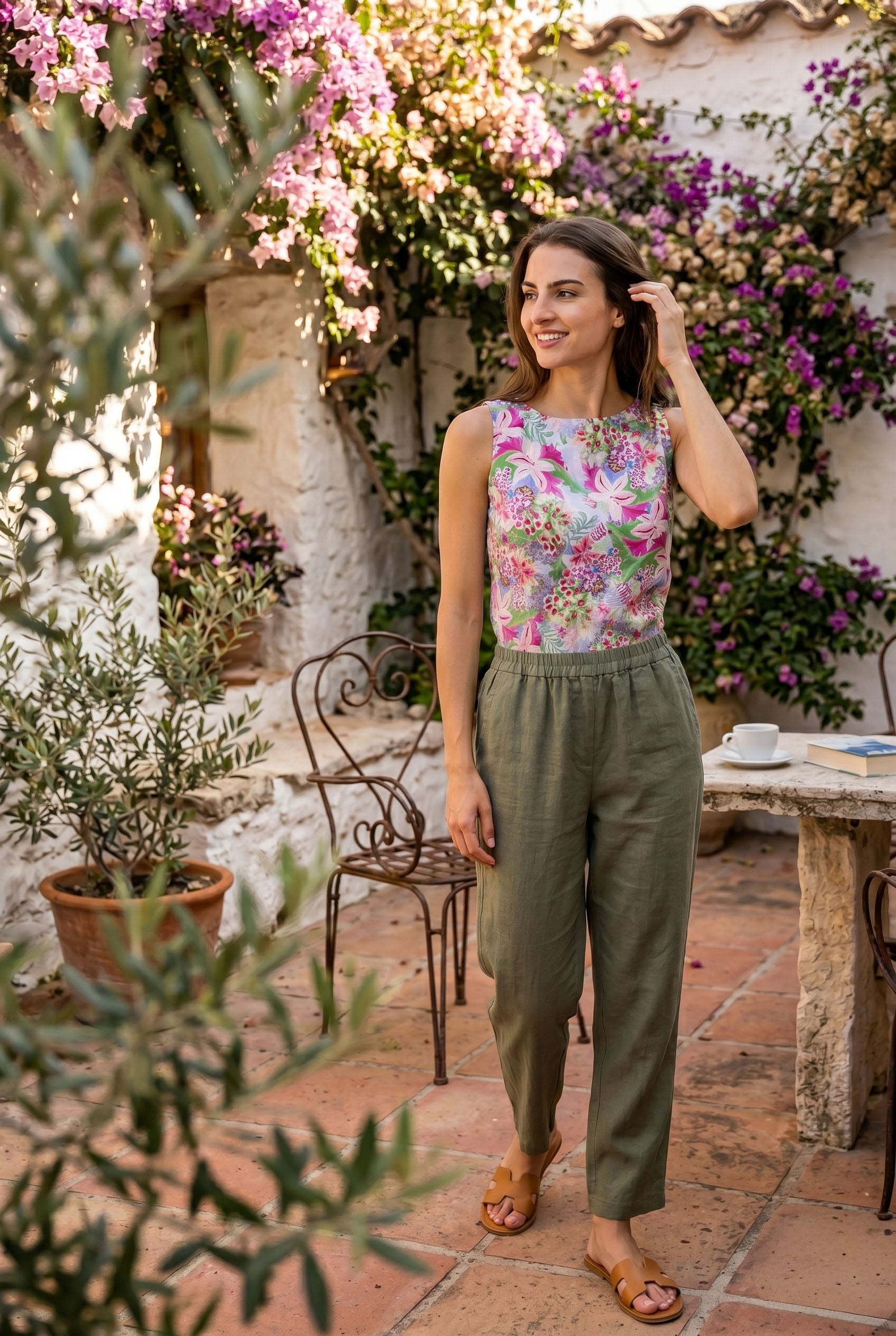 Woman standing in a garden with flowers and a rustic building in the background
