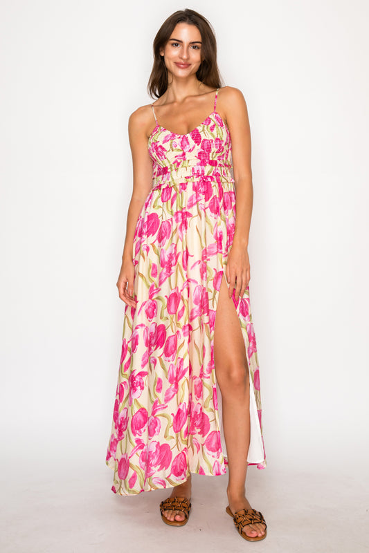 Model wearing the Lonian's Bloom Maxi Dress, an ivory floor-length dress with a large pink floral print, featuring a smocked bodice and a high side slit.