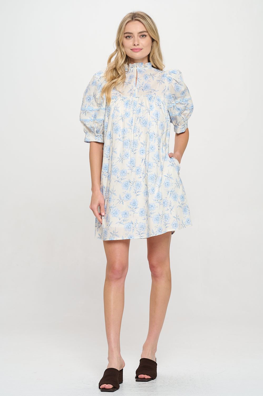 Model wearing a floral puff sleeve mini dress with a high neckline and relaxed fit.