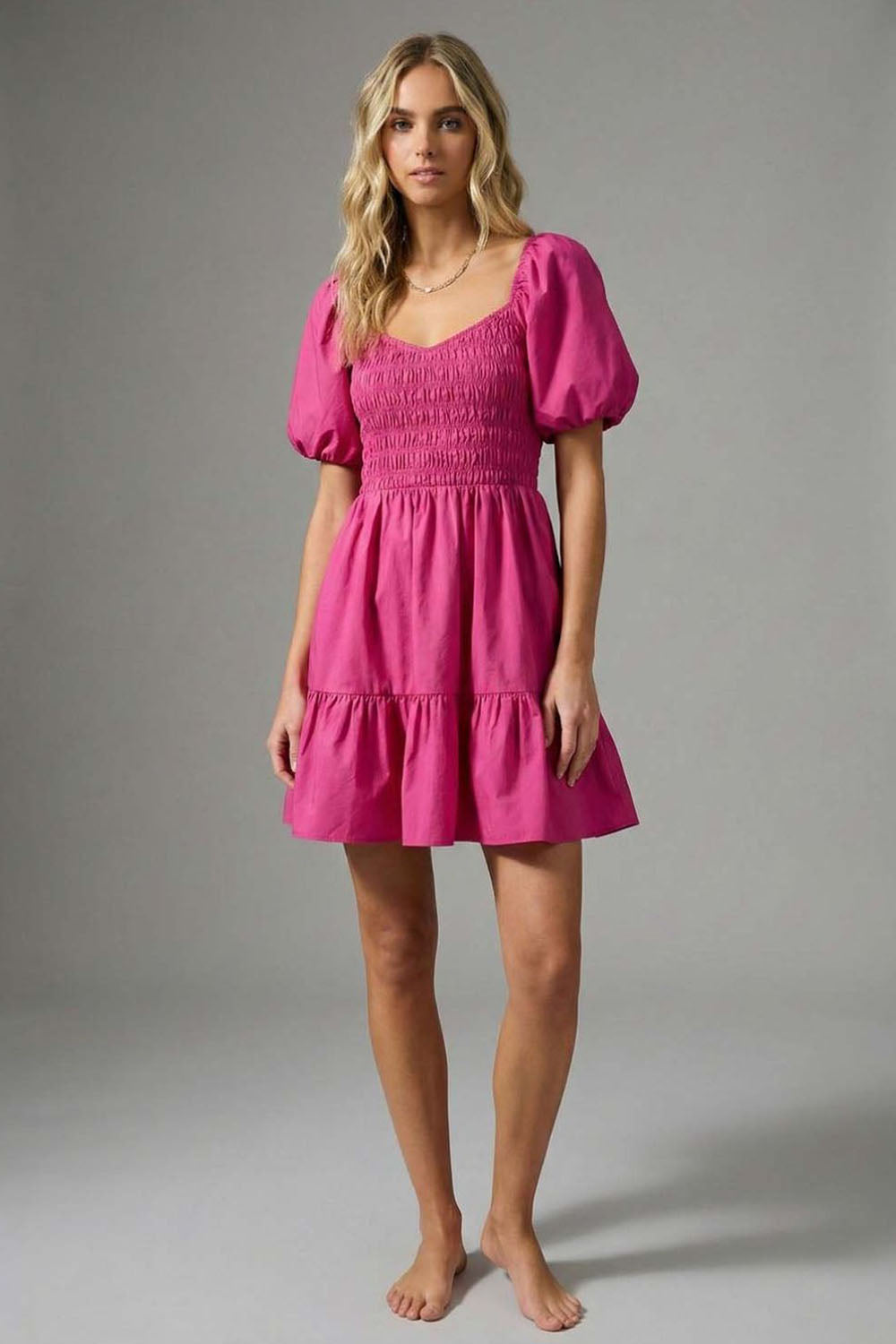 Model wearing the Deep Pink Puff Sleeve Dress, a vibrant magenta mini dress featuring a smocked bodice, sweetheart neckline, and voluminous puff sleeves.