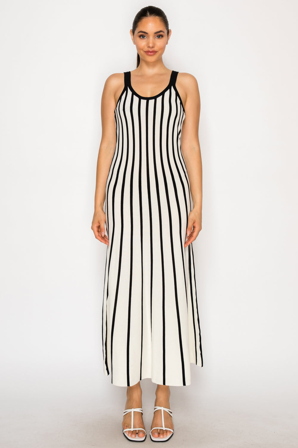 Model wearing the Ivory Sweater Midi Dress, a black and white vertical striped knit dress with a scoop neck.
