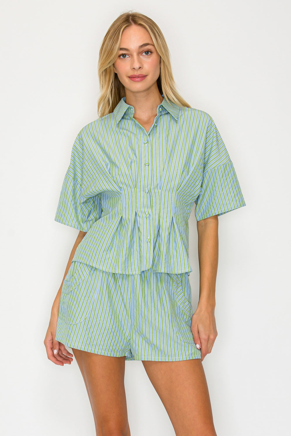 Woman wearing a green and white striped shirt and shorts set on a white background